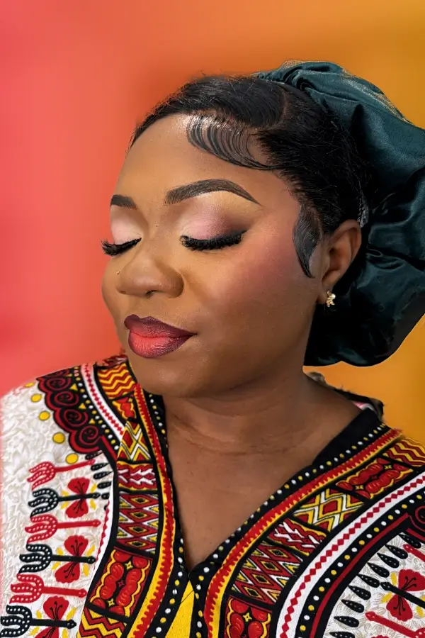 Portrait d'une femme maquillée avec élégance, arborant un maquillage Soft-Glam aux tons roses et rouges avec un rouge à lèvres profond et des cils volumineux.